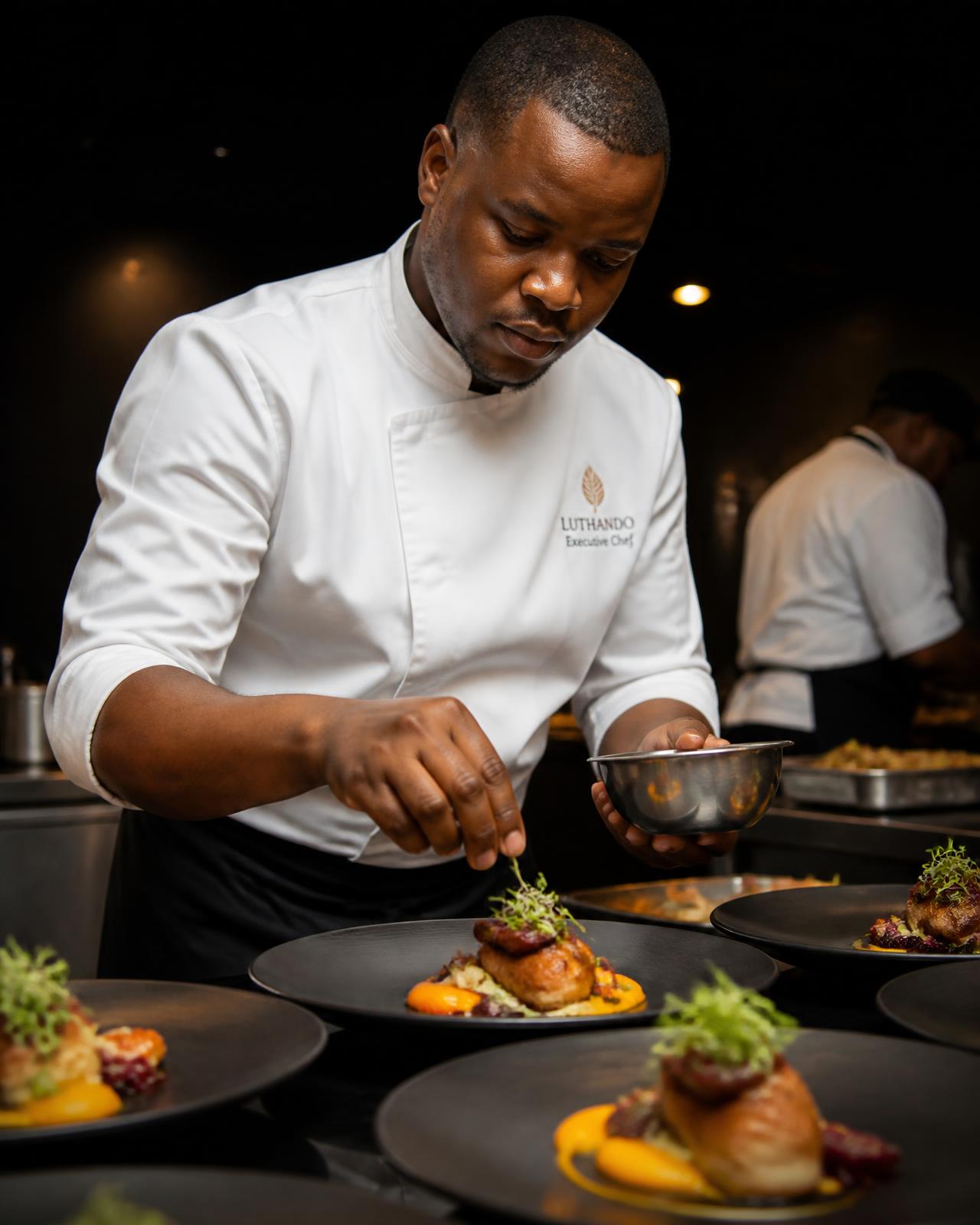 Chef garnishing plated dishes in a professional catering kitchen
