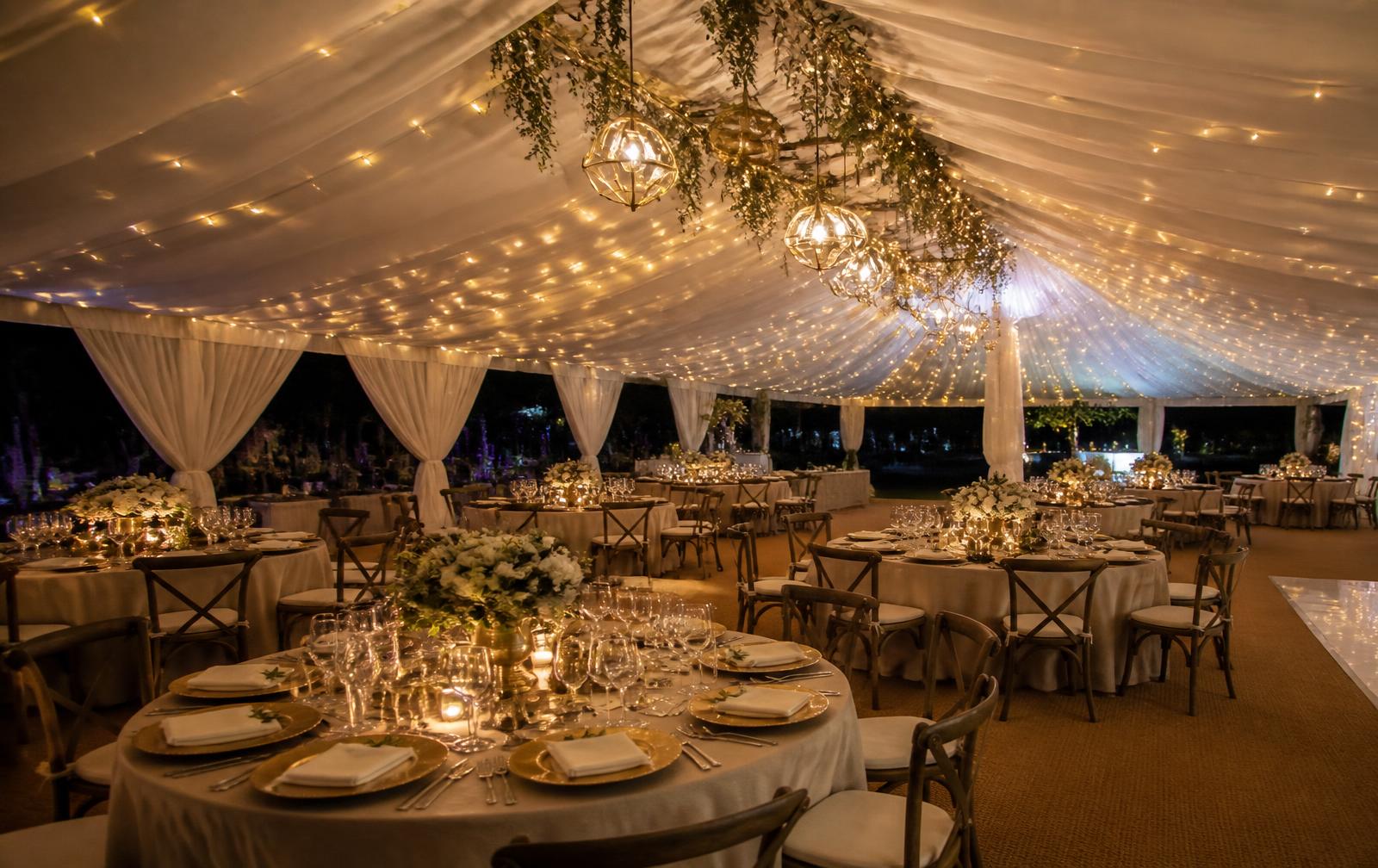 Event marquee at night with fairy lights and set round tables