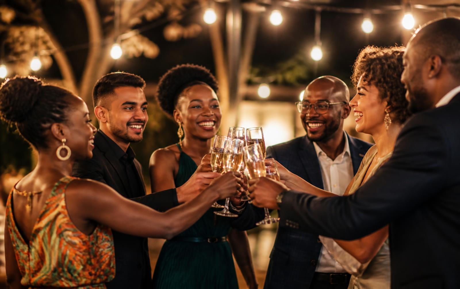 Friends toasting champagne under string lights at an evening celebration